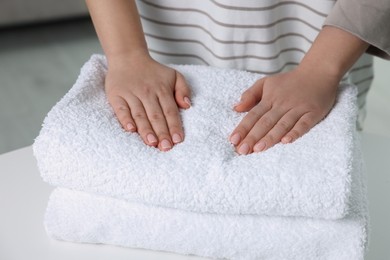 Photo of Woman touching soft white towel indoors, closeup