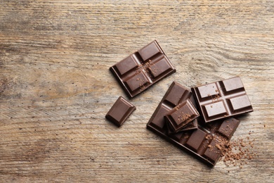 Photo of Tasty chocolate on wooden background, flat lay. Space for text