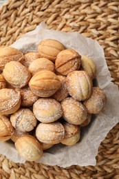 Bowl of delicious nut shaped cookies on wicker mat, top view