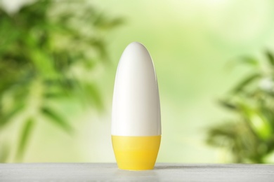 Photo of Deodorant container on white wooden table against blurred background