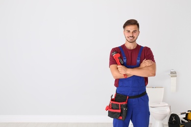 Photo of Young man with plumber wrench and toilet bowl on background