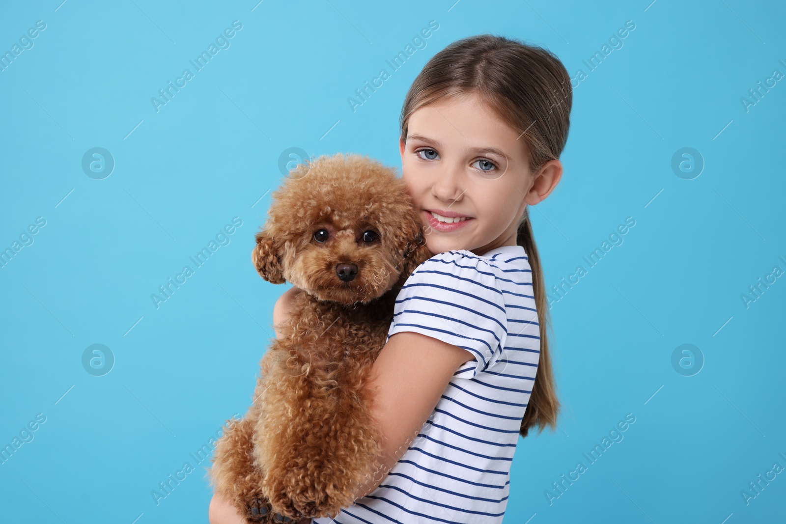 Photo of Little child with cute puppy on light blue background. Lovely pet