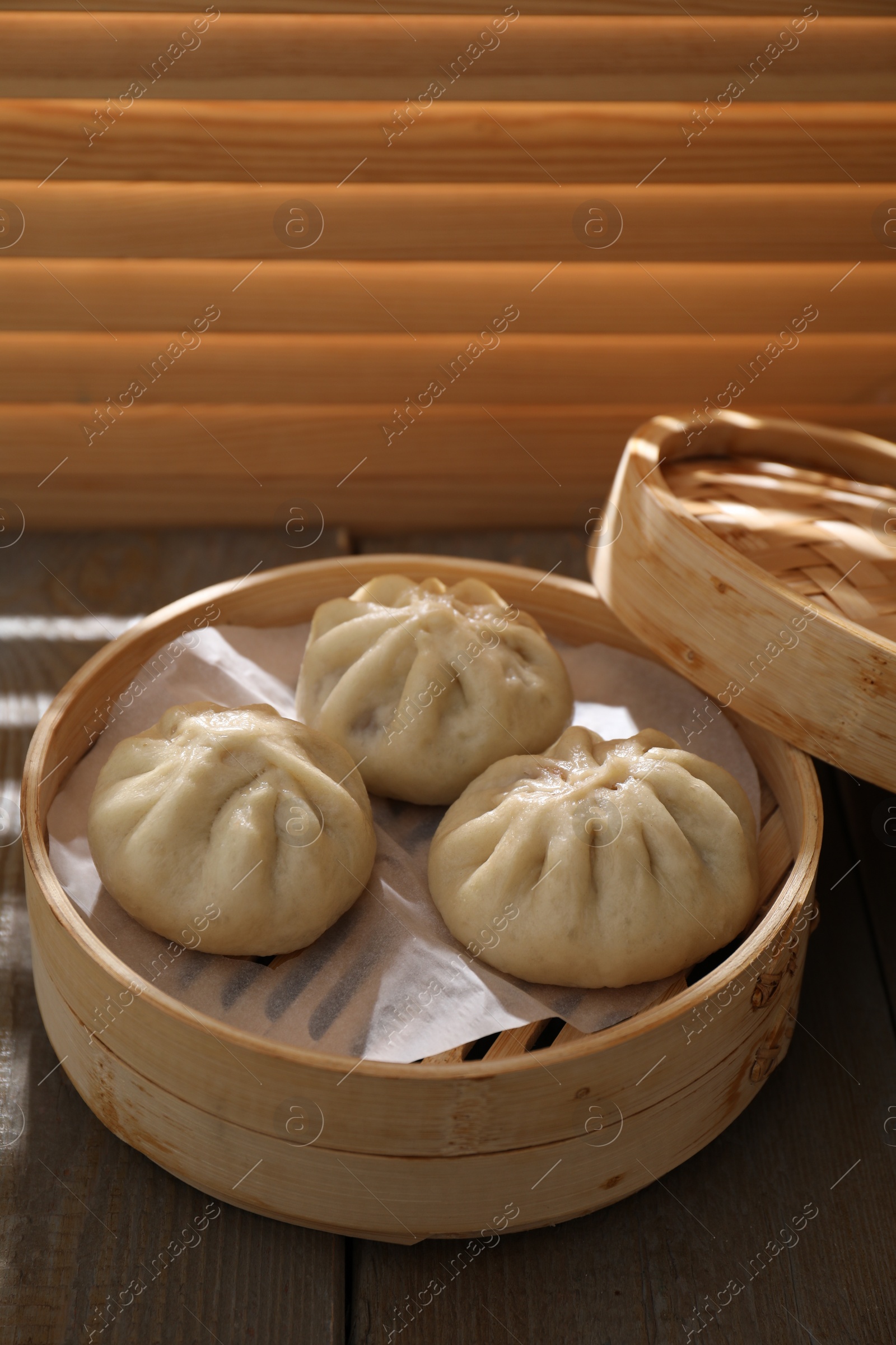 Photo of Delicious bao buns (baozi) on wooden table, closeup