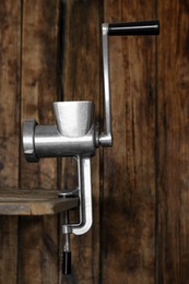 Photo of Metal manual meat grinder on table against wooden background
