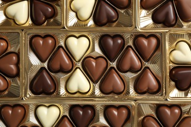 Beautiful heart shaped chocolate candies in box as background, top view