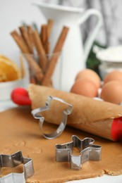 Photo of Cookie cutters, dough and rolling pin on white table, closeup. Christmas biscuits