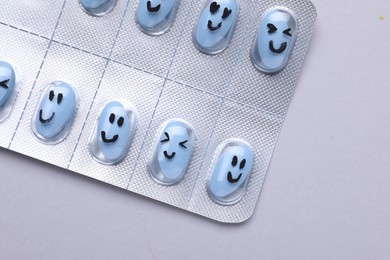 Antidepressants with different emoticons on grey background, top view