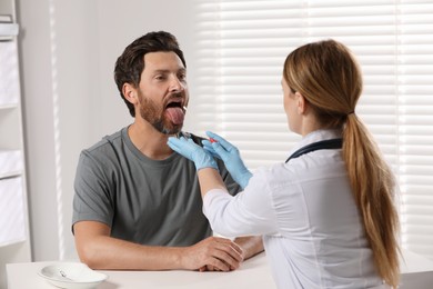 Photo of Doctor taking throat swab sample from man`s oral cavity indoors
