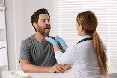 Doctor taking throat swab sample from man`s oral cavity indoors