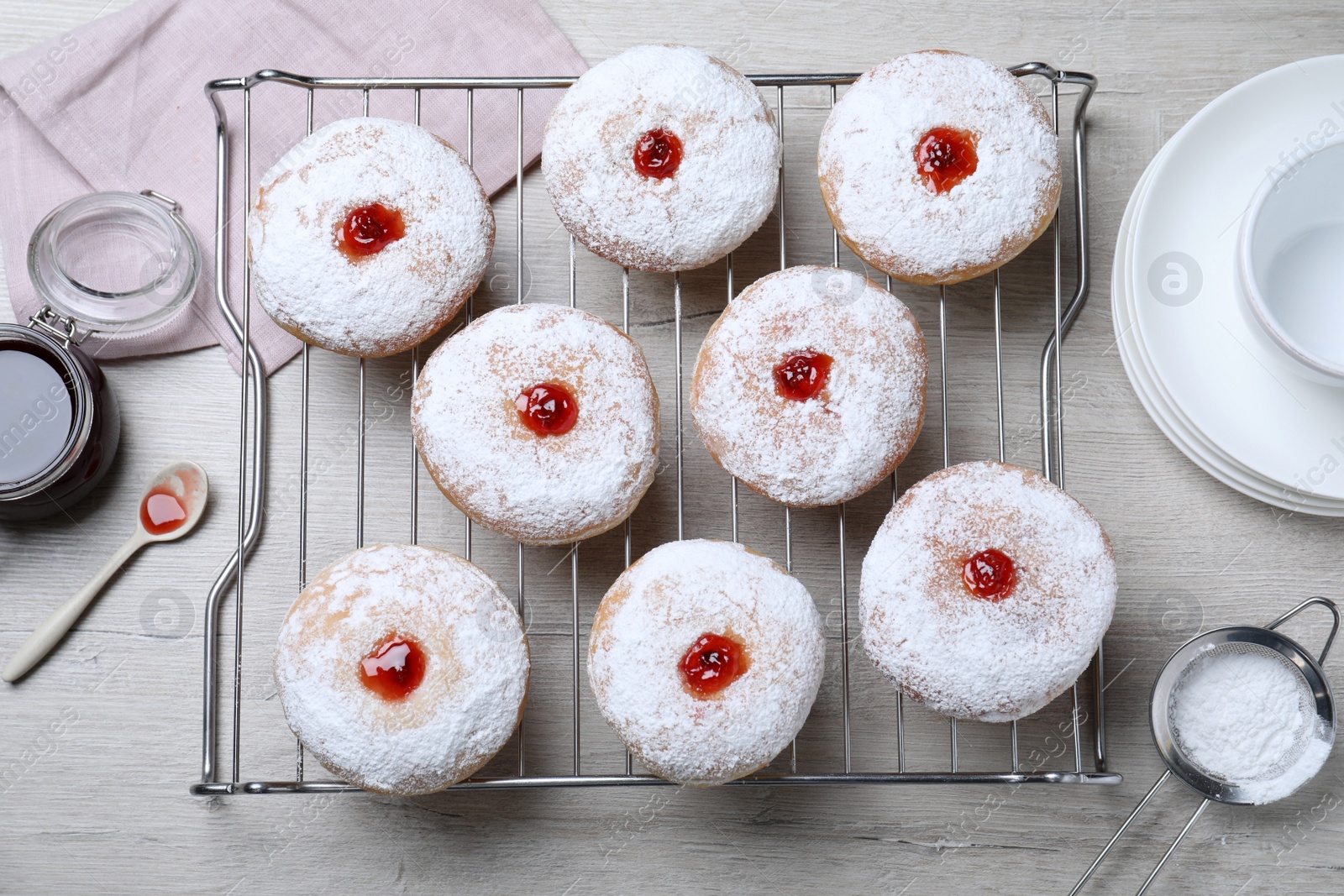 Photo of Many delicious donuts with jelly and powdered sugar on wooden table, flat lay