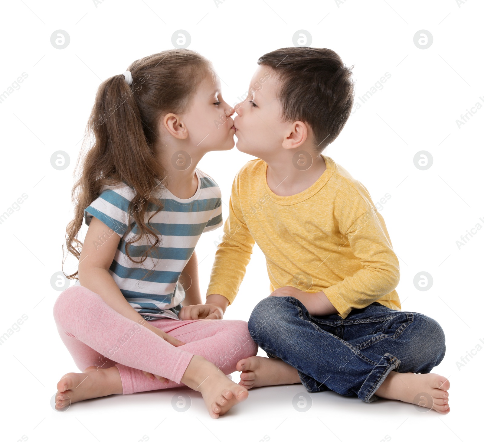 Photo of Cute little boy and girl kissing on white background