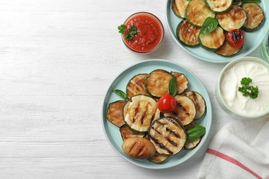 Photo of Flat lay composition with delicious grilled zucchini slices on white wooden table. Space for text