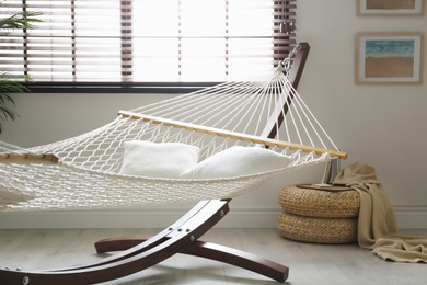 Photo of Comfortable net hammock with pillows in stylish room. Interior design