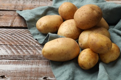 Photo of Raw fresh potatoes and napkin on wooden table