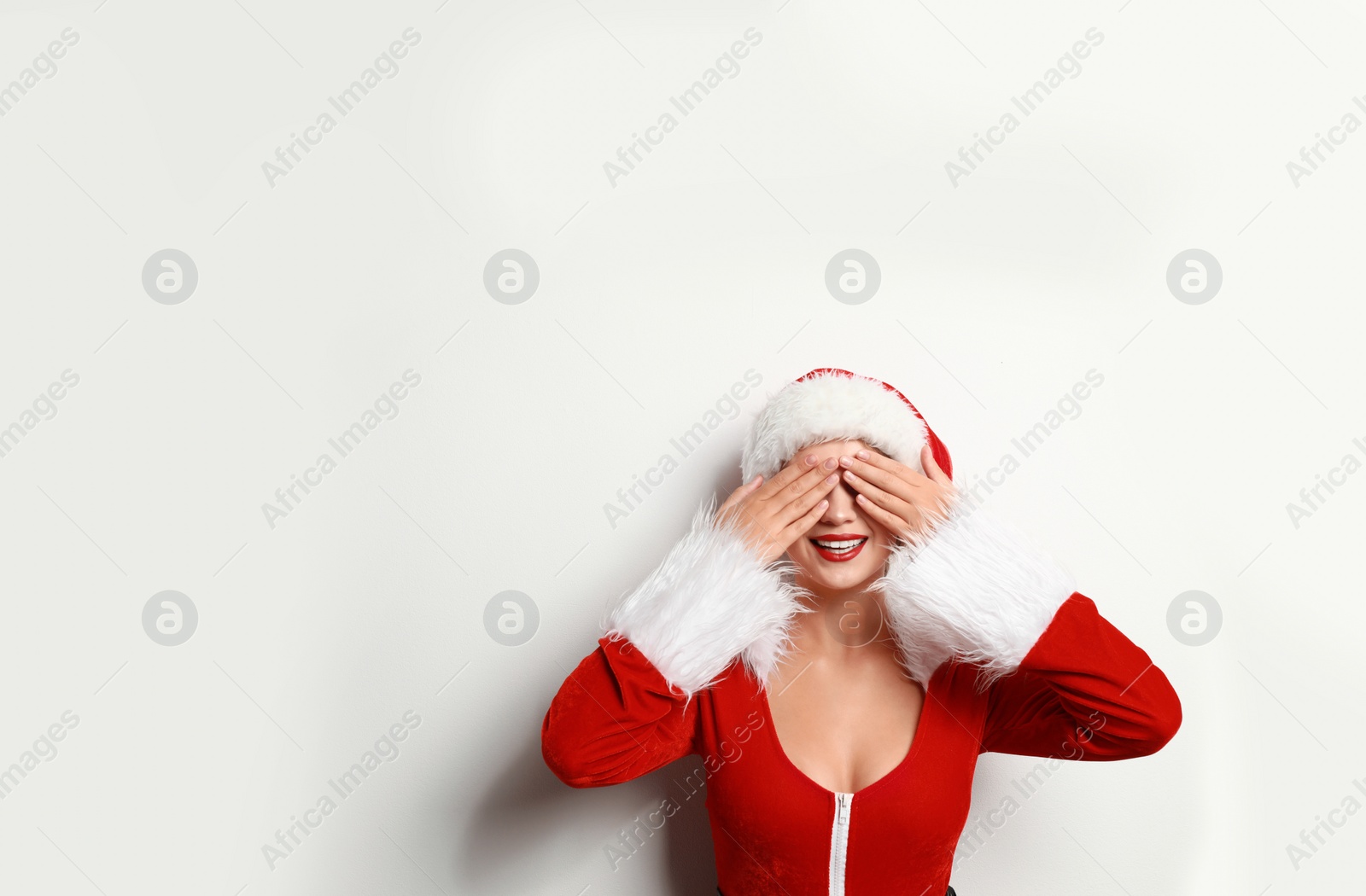 Photo of Beautiful Santa girl on light background, space for text. Christmas eve