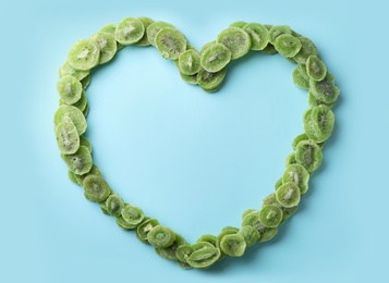 Heart shaped frame made of kiwi on color background, top view with space for text. Dried fruit as healthy food