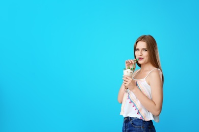 Photo of Young woman with glass of delicious milk shake on color background