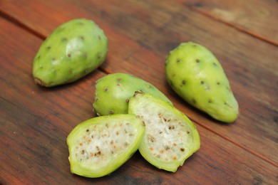 Photo of Tasty prickly pear fruits on wooden table, above view