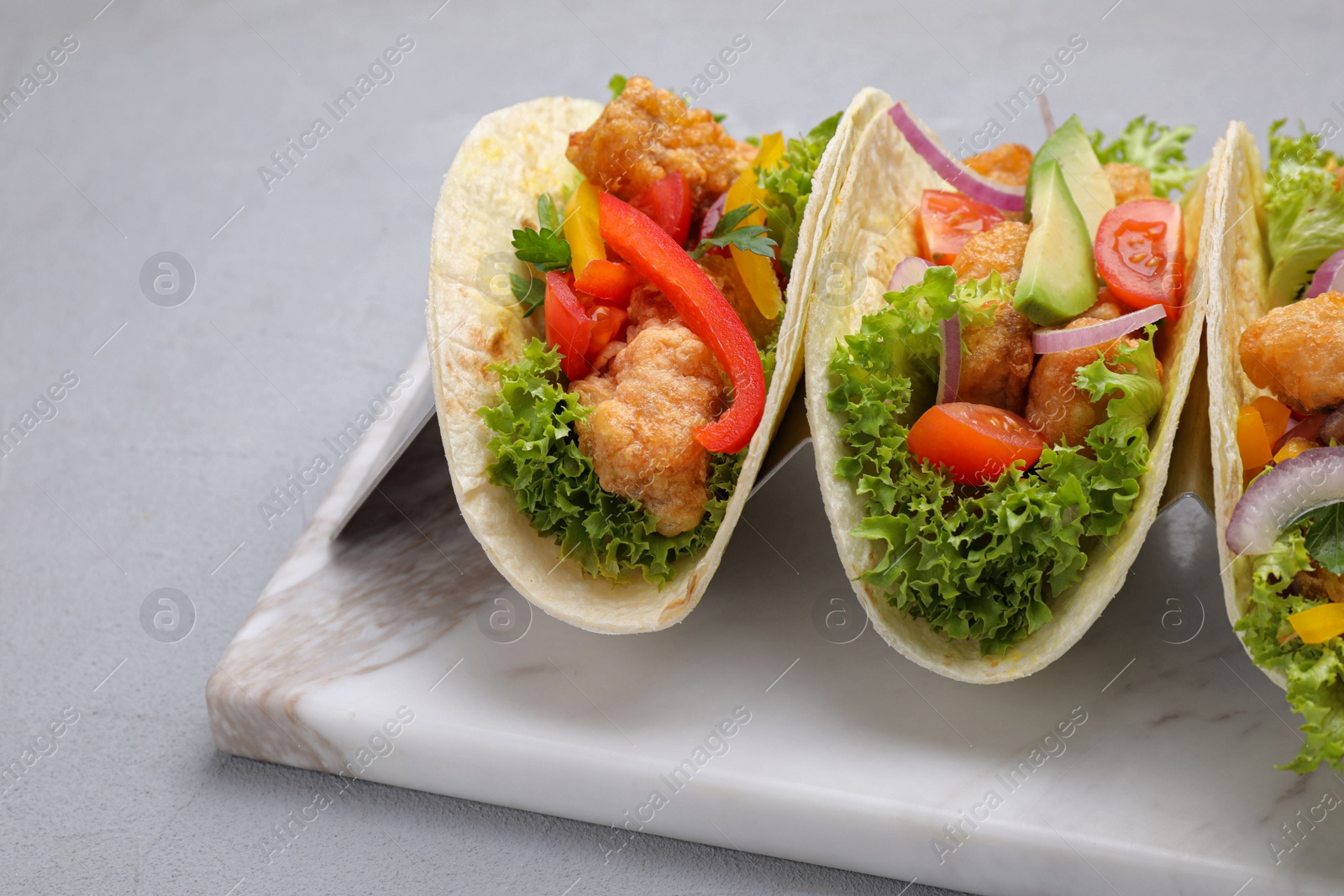 Photo of Delicious fish tacos served on grey table, closeup