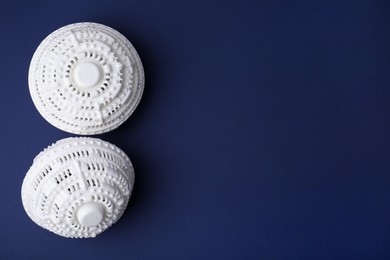 Photo of Laundry dryer balls on dark blue background, flat lay. Space for text