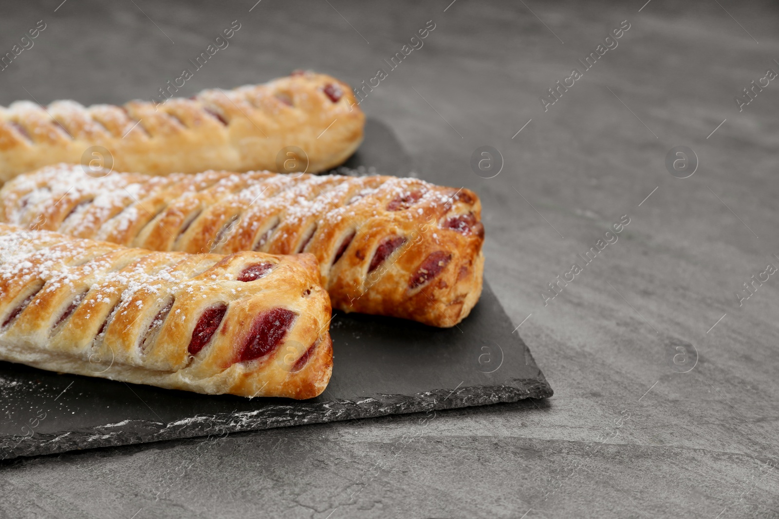 Photo of Fresh tasty puff pastry with sugar powder on grey table, closeup. Space for text