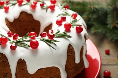 Traditional Christmas cake decorated with glaze, pomegranate seeds, cranberries and rosemary on table, closeup