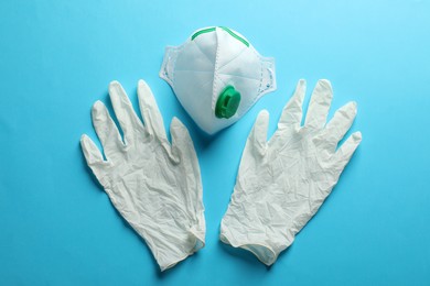 Photo of Medical gloves and respiratory mask on light blue background, flat lay. Safety equipment