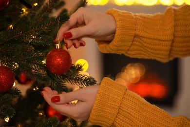 Photo of Woman decorating Christmas tree at home, closeup