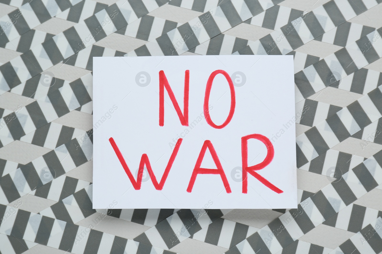 Photo of Card with phrase No War and adhesive tape on light background, top view
