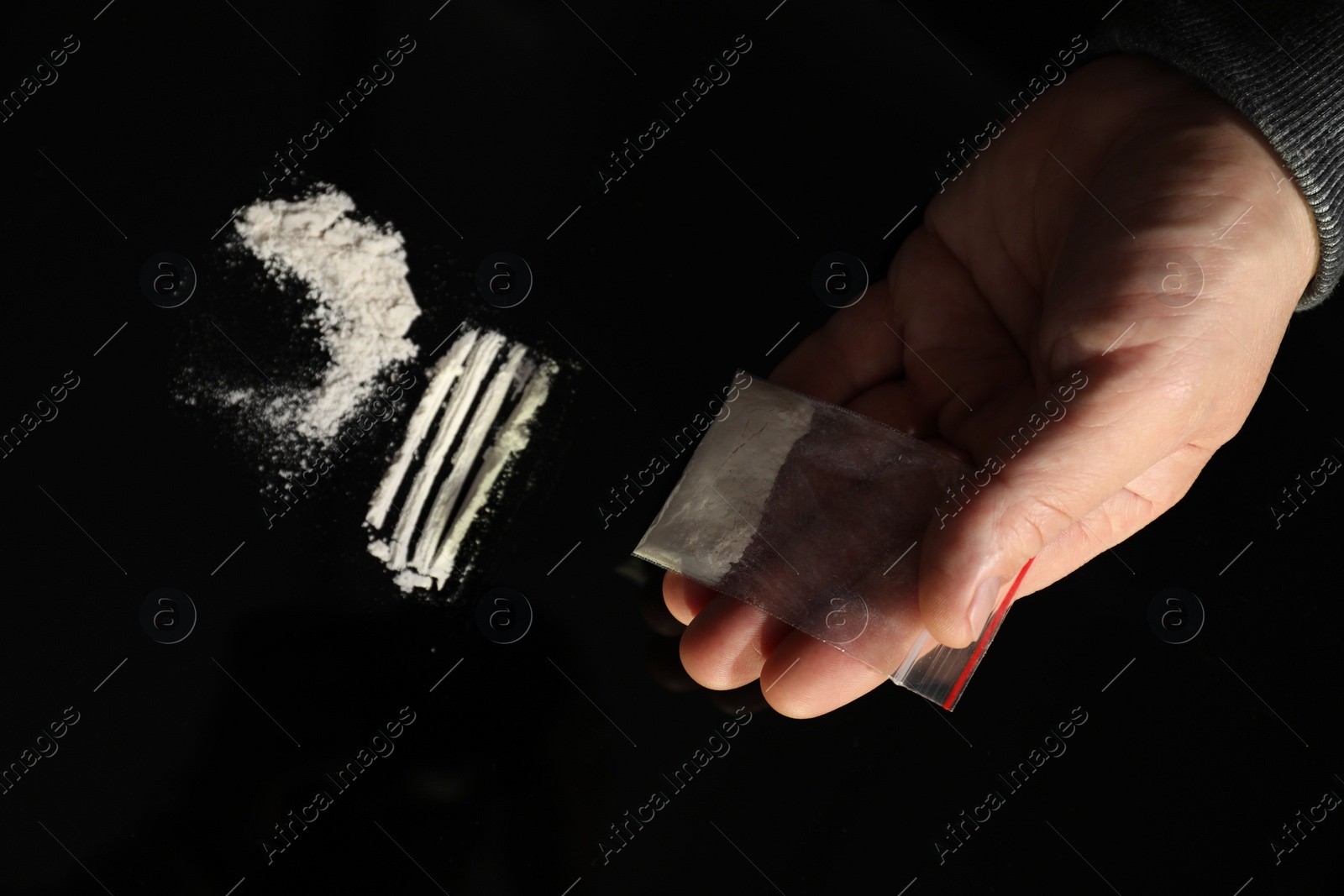 Photo of Drug addiction. Man with cocaine at black table, top view
