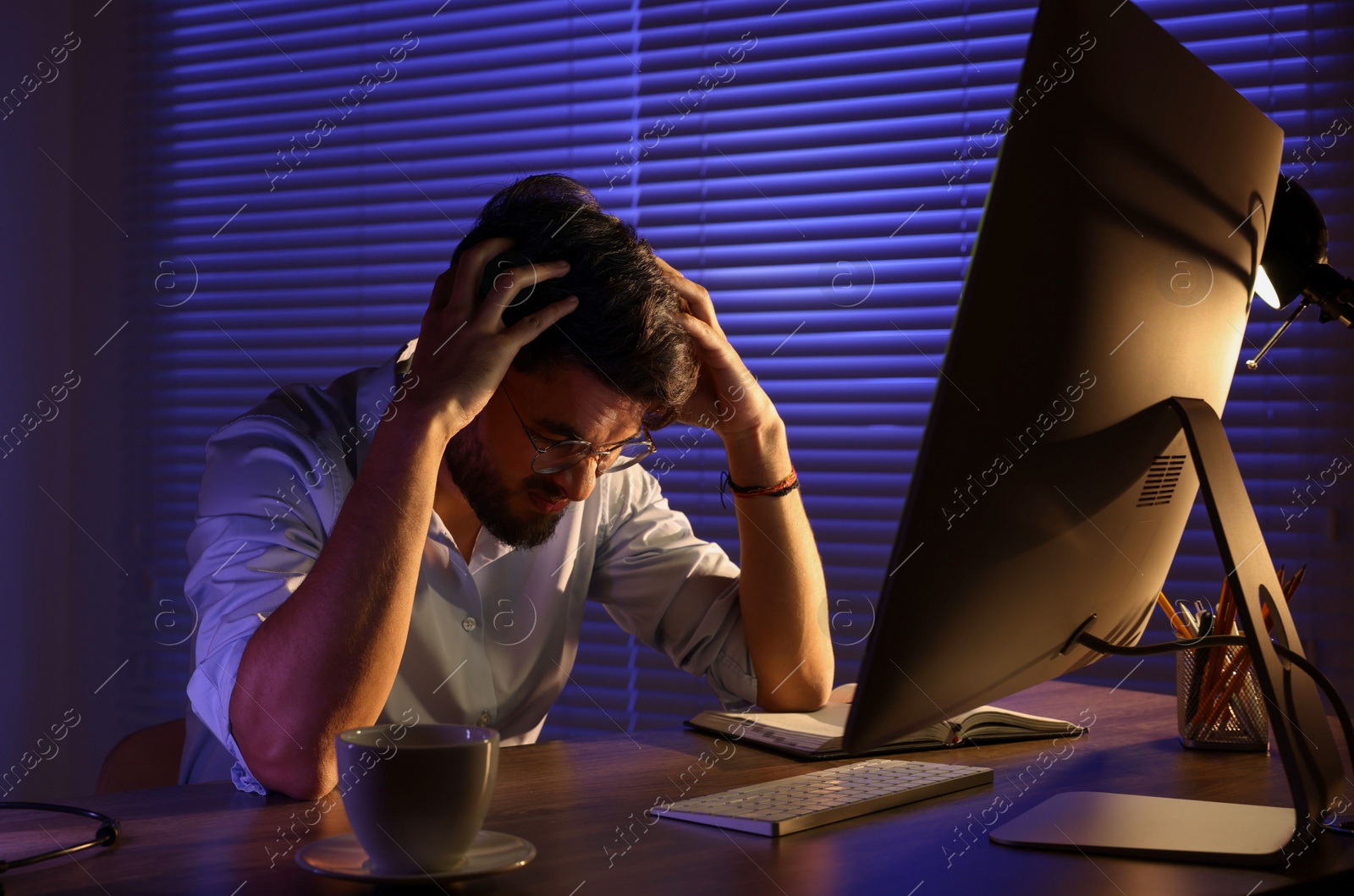 Photo of Tired young man working late in office