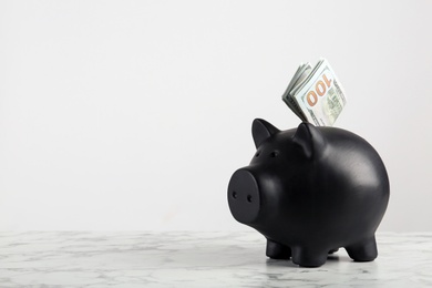 Photo of Piggy bank with dollar banknotes on table against white background. Space for text