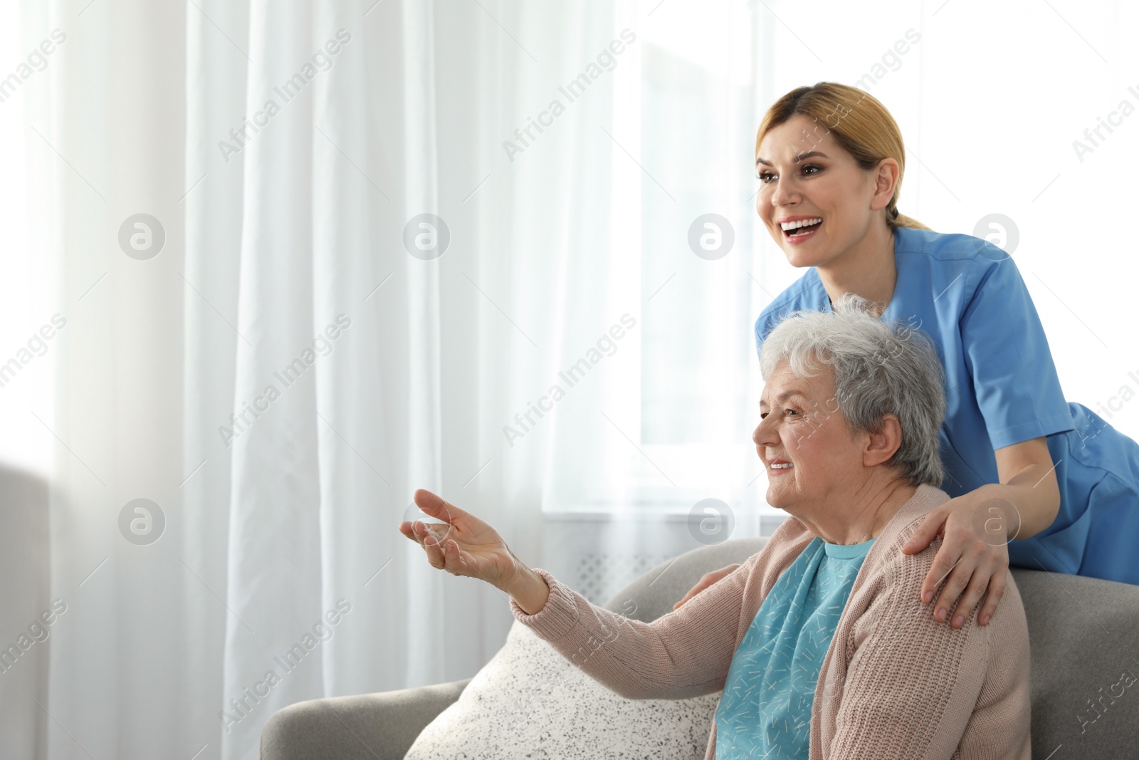 Photo of Nurse with elderly woman indoors, space for text. Assisting senior people