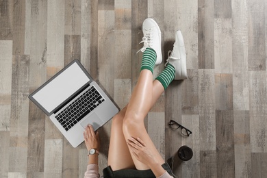 Photo of Top view of woman with laptop sitting on floor, closeup. Mockup for design