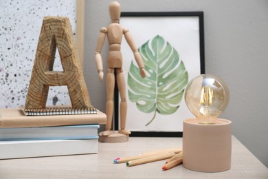 Photo of Modern night lamp, books and decor on table near grey wall. Space for text