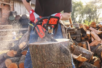 Photo of Man sawing wooden log outdoors, closeup view