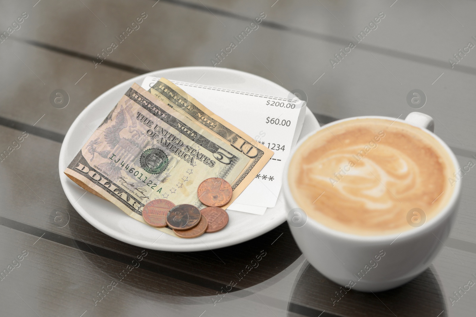 Photo of Tips, receipt and cup with coffee on wooden table