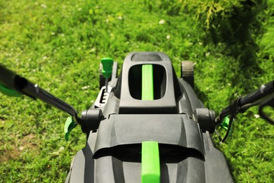 Photo of Lawn mower on green grass in garden, above view