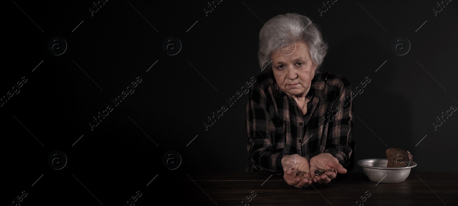 Image of Poor mature woman with coins and bread in bowl at table, space for text. Banner design