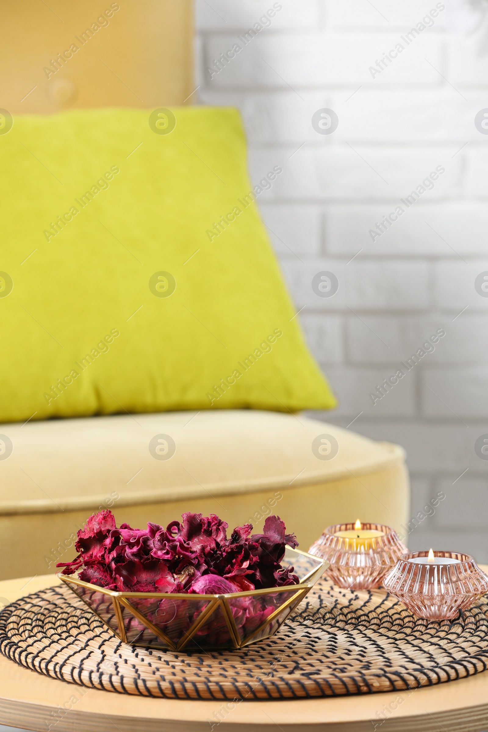 Photo of Aromatic potpourri of dried flowers in bowl and burning candles on wooden table indoors. Space for text