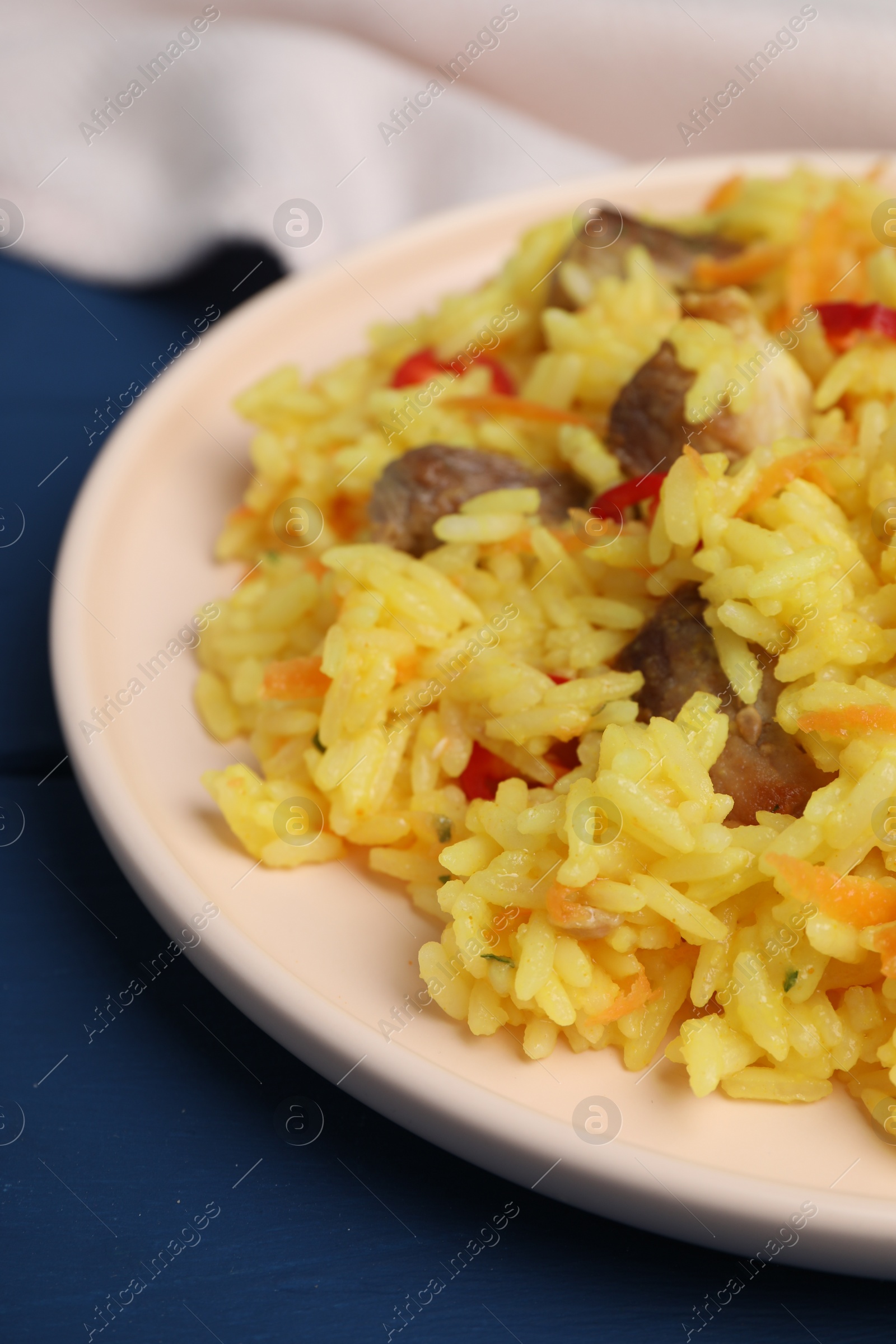 Photo of Delicious pilaf with meat on blue table, closeup