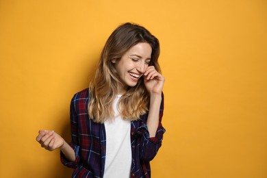 Photo of Cheerful young woman laughing on yellow background