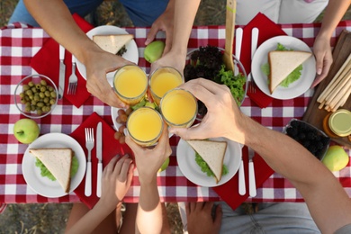 Photo of Young people having picnic at table in park, top view