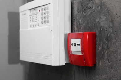 Photo of Fire alarm push button and house security system control panel on grey wall