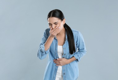 Photo of Woman suffering from stomach ache and nausea on grey background. Food poisoning