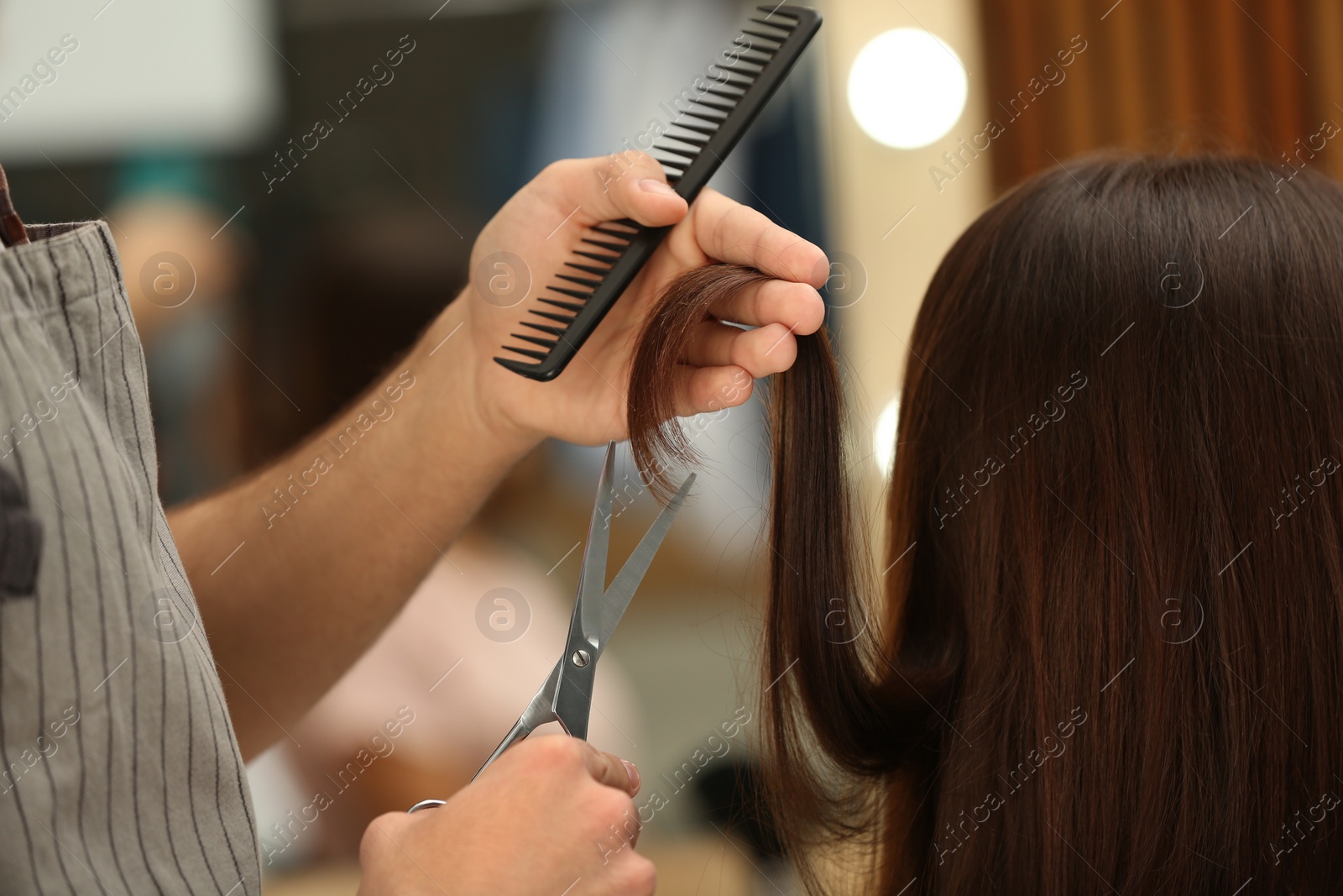 Photo of Barber making stylish haircut with professional scissors in beauty salon, closeup