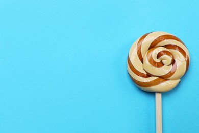Sweet colorful lollipop on light blue background, top view. Space for text