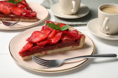 Photo of Piece of delicious strawberry tart with mint on white wooden table, closeup