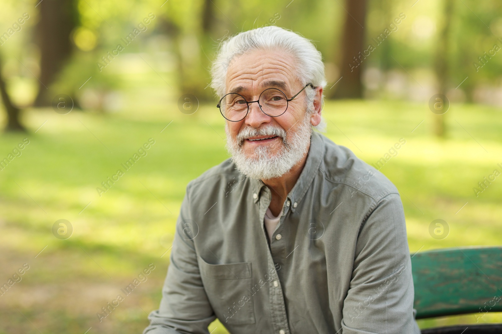 Photo of Portrait of happy grandpa with glasses on bench in park