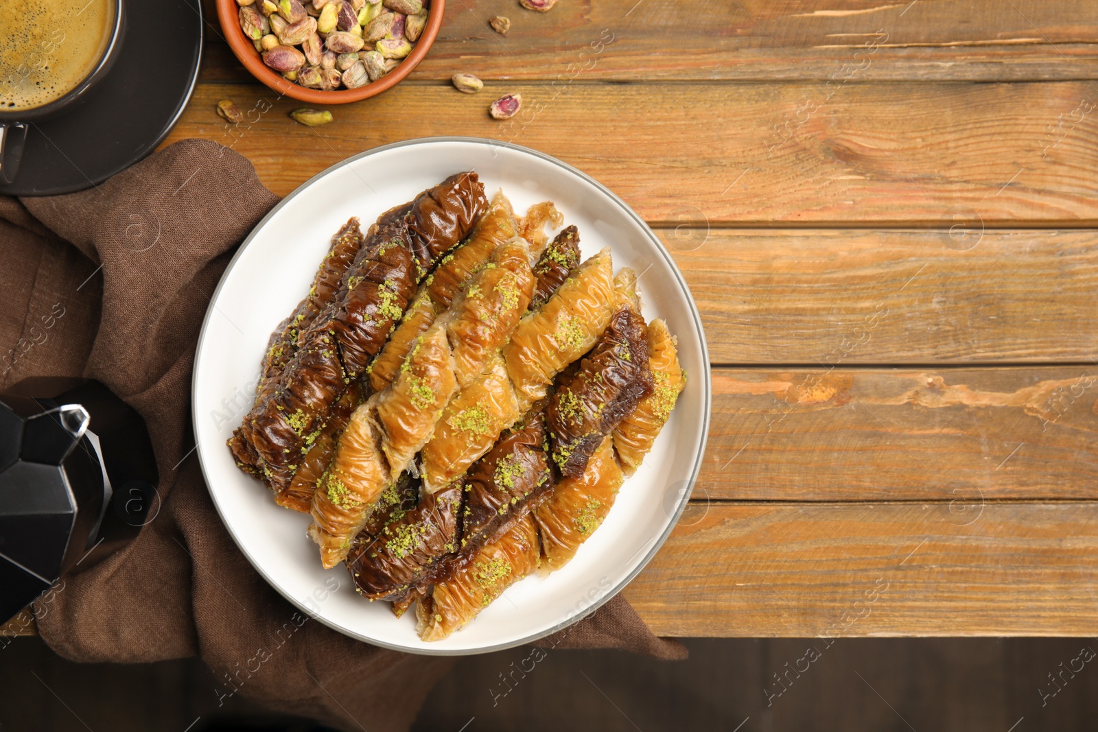 Photo of Delicious sweet baklava with pistachios and aromatic coffee on wooden table, flat lay. Space for text